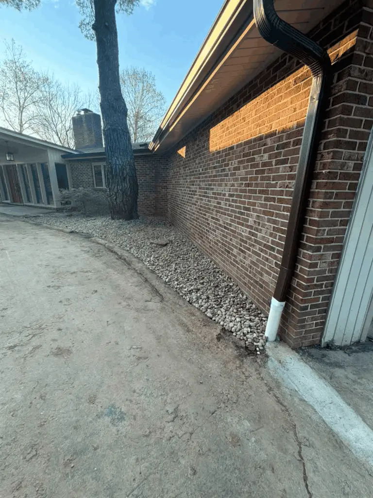 River rock finished over a buried French drain beside a Des Peres, MO home