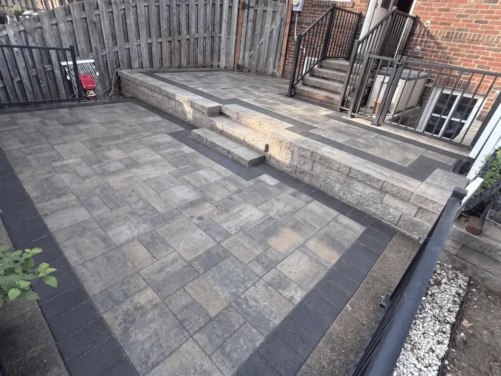 Two-tier paver patio replacement in Ballwin, MO, with Belgard pavers, dark border and block wall