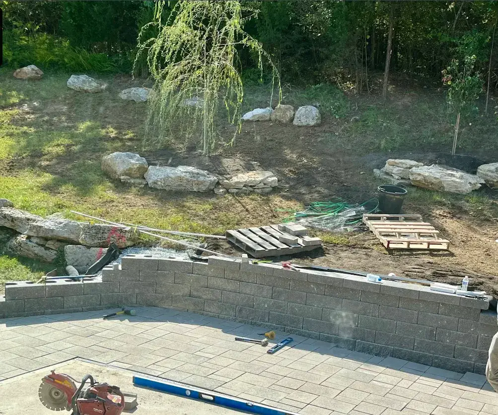 Segmental block retaining wall under construction beside new pavers in Valley Park, MO
