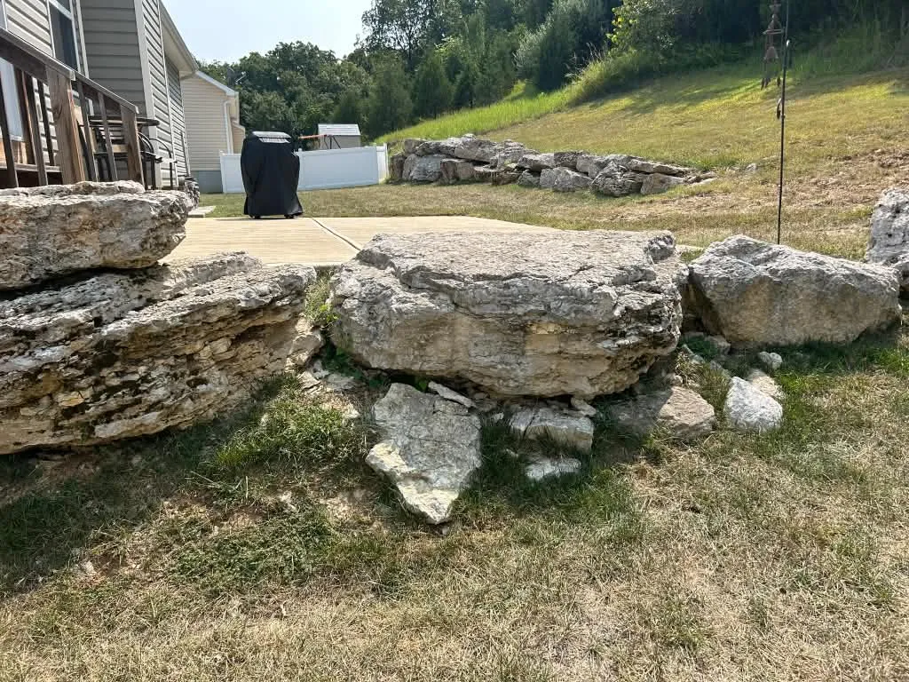 Loose boulders beside a small concrete patio on a hillside in Valley Park, MO