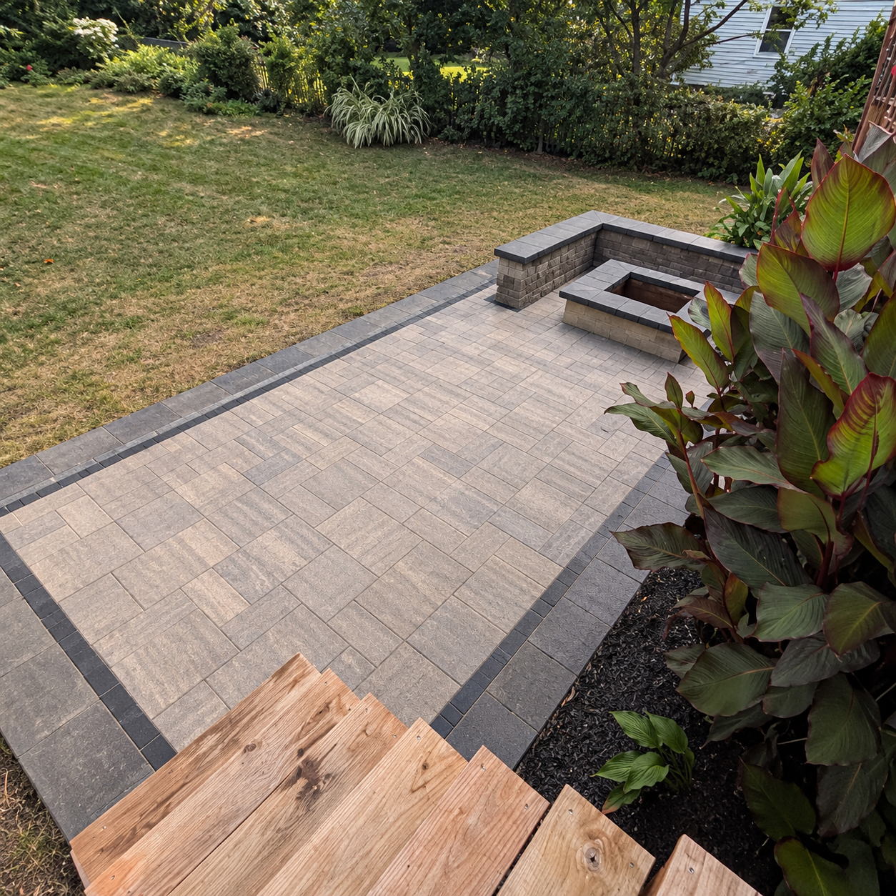 Paver patio with a square fire pit and seating wall seen from the deck in Kirkwood, MO