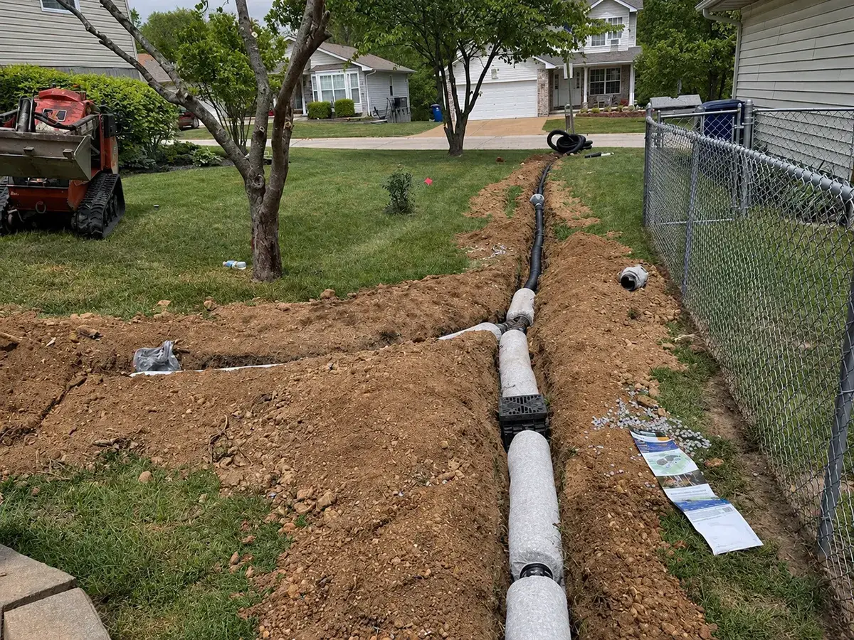 EZ-Drain French drain and drain box in an open trench along a fence in Brentwood, MO