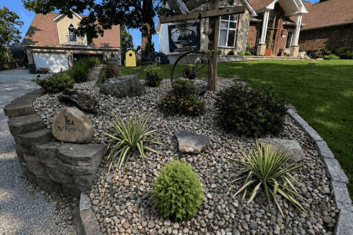 The completed retaining wall creates a strong finished edge near the home while the surrounding plantings help integrate the new stonework into the front landscape.